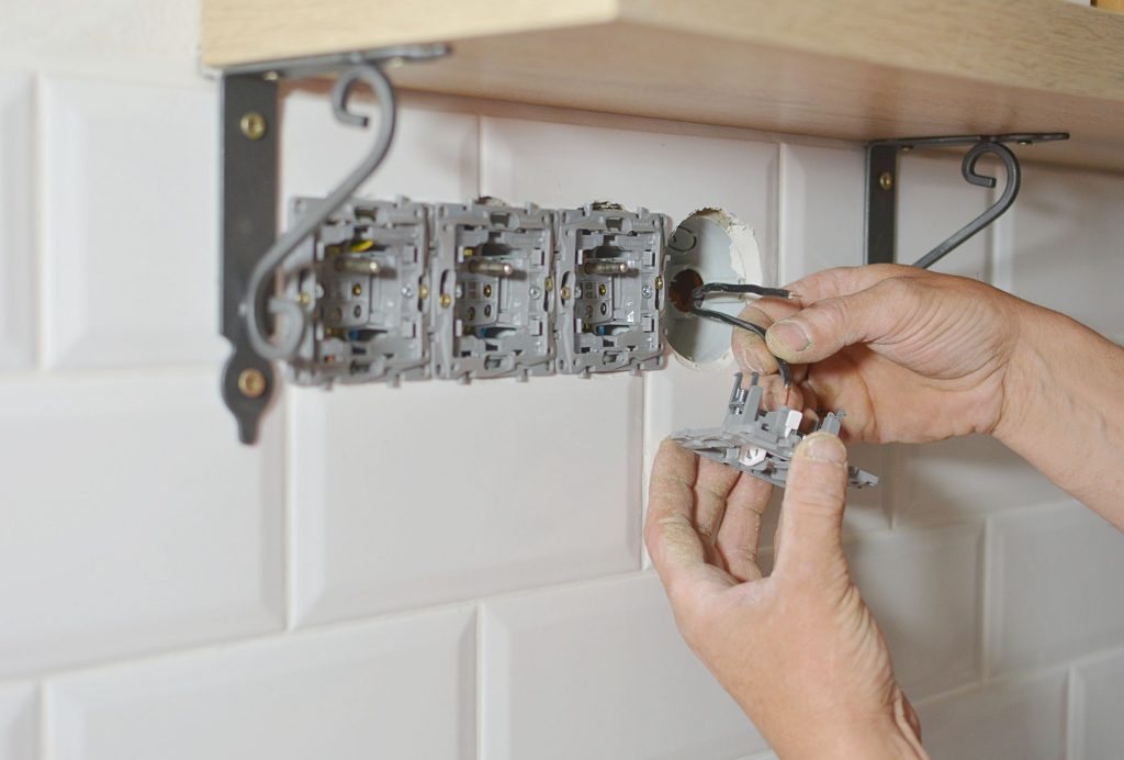 Electrician installing wall socket in new building,