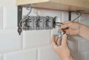Electrician installing wall socket in new building,